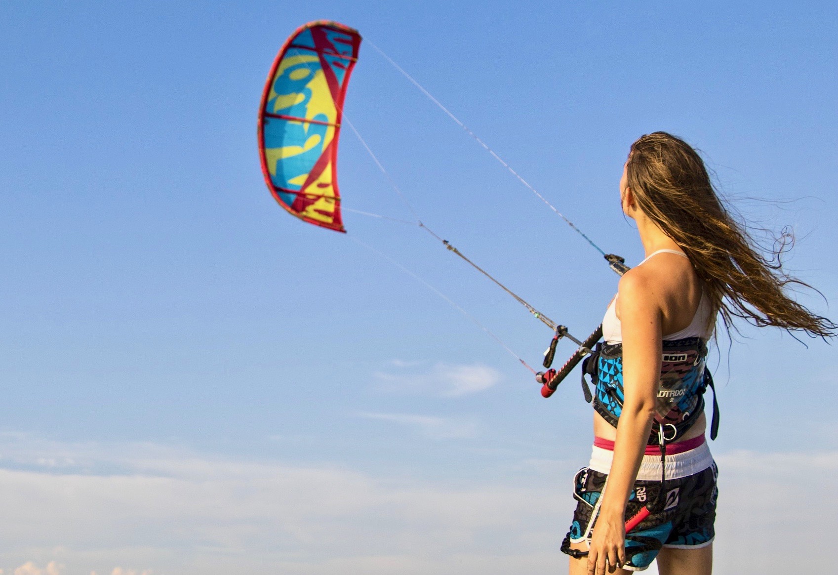 Una niña practicando su habilidad de control de kite antes de practicar kitesurf en el mar.