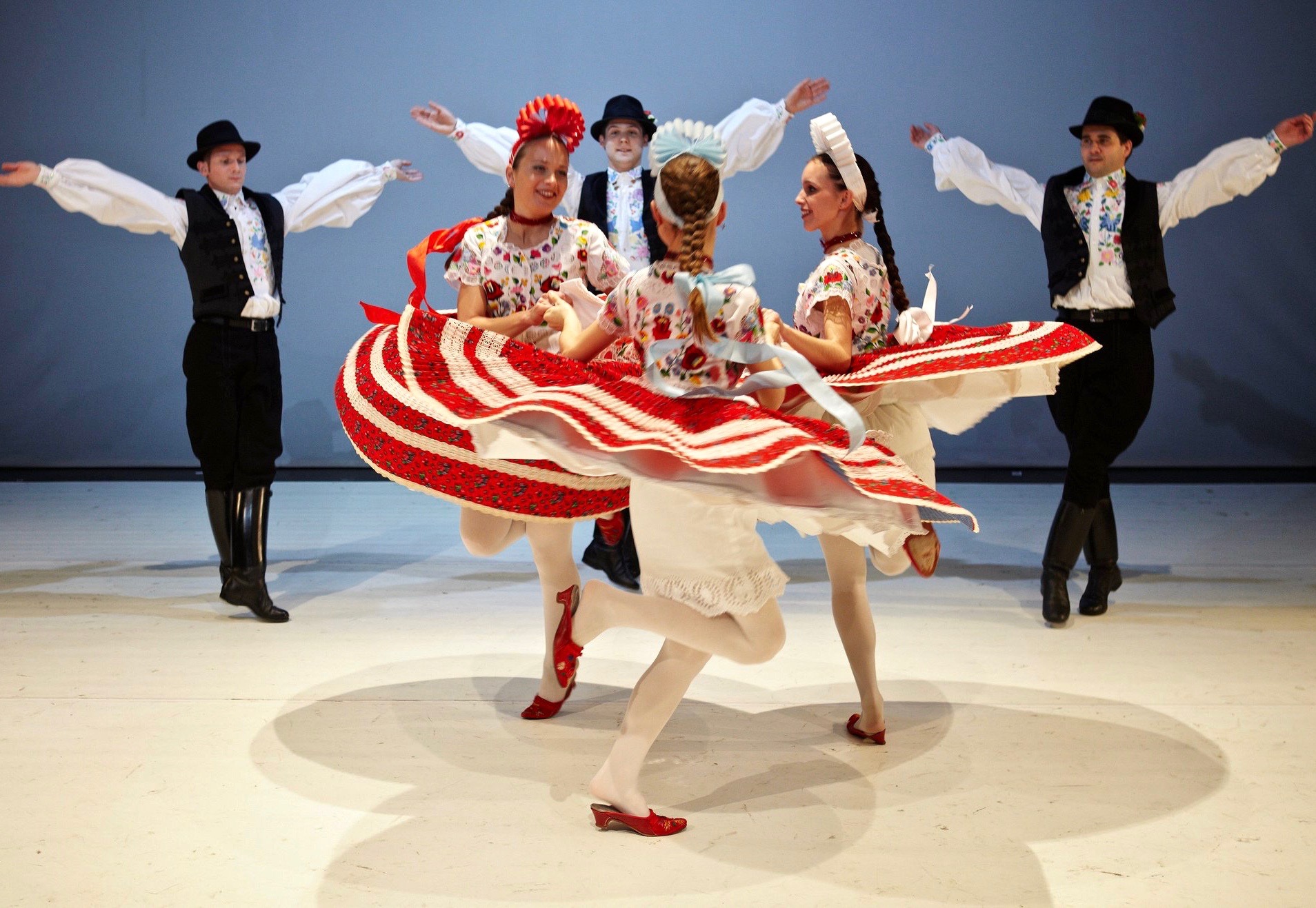 Bailarines folclóricos húngaros vestidos con trajes de colores que bailan una danza tradicional.