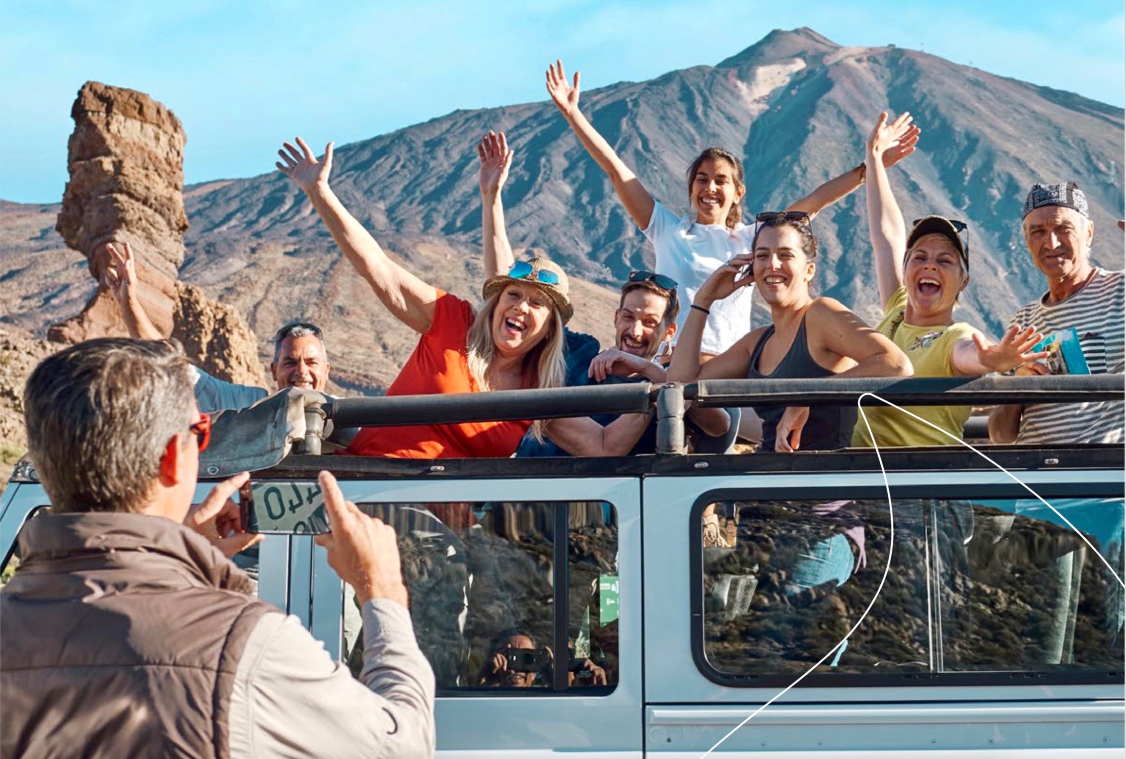 Un grupo de viajeros en una excursión turística felizmente posando para la foto frente al volcán Teide
