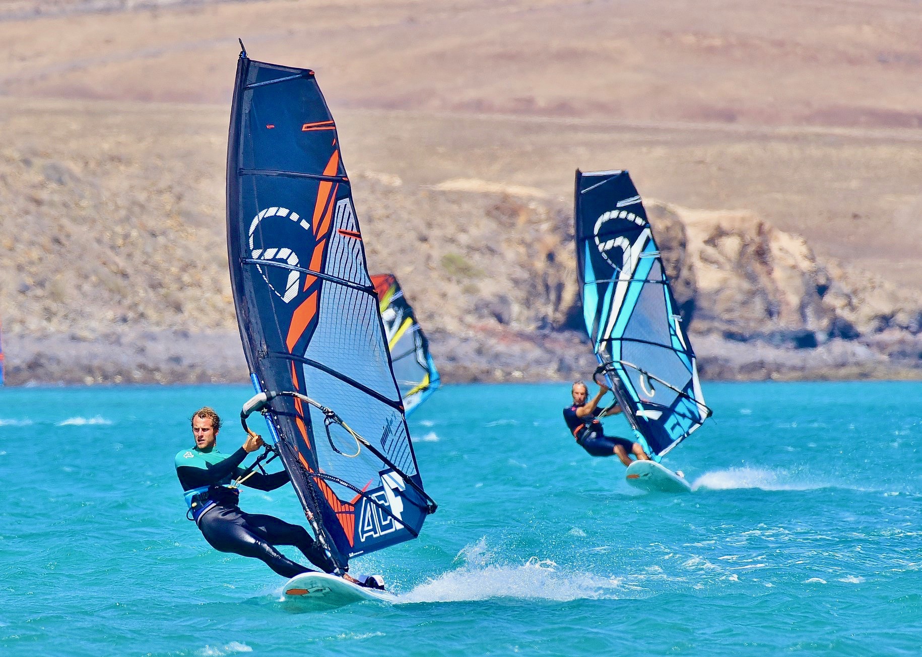 Dos windsurfistas practicando sus habilidades de windsurf en aguas turquesas